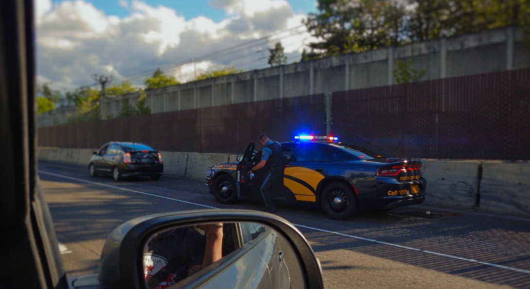 A police officer pulls over a driver on the side of a highway.