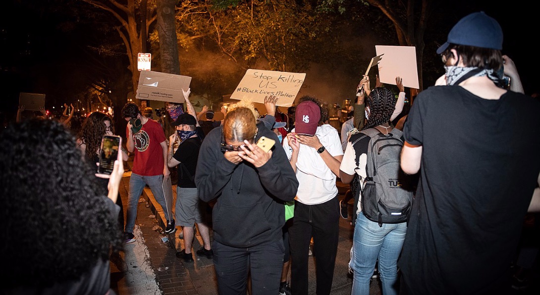 Protestors wipe their eyes after tear gas was deployed by police at a George Floyd protest in Washington DC.