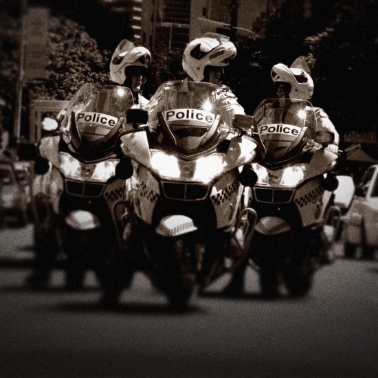 Three police officers drive down a street on motorcycles.